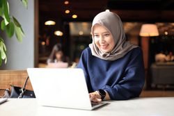 Muslim Asian Women with Hijab Working at a Cafe and using Laptop Computer.