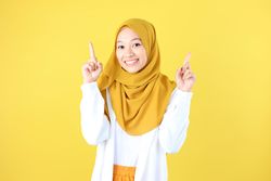 Look There, Excited Muslim Woman in Hijab Pointing Upwards at Copy Space