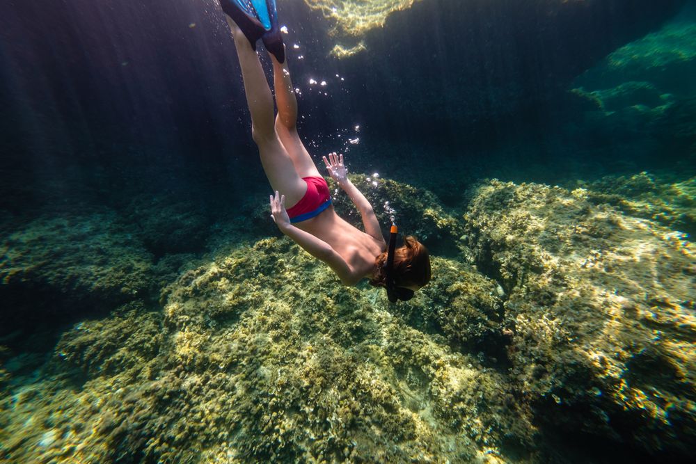 Anonymous boy diving on seawater with reefs