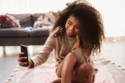 Black woman taking selfie on floor