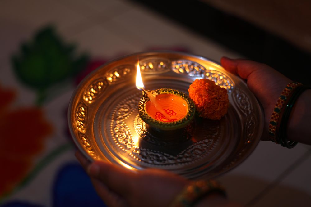 Person holding golden tray with candle on it