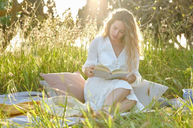 Content woman reading book on grassy meadow