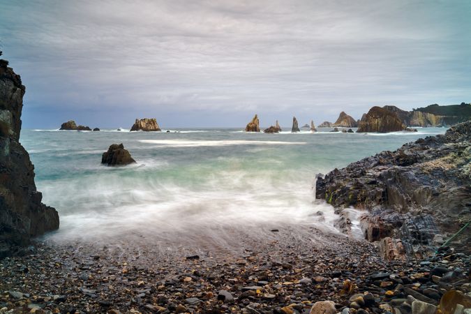 Rocky peaks protrude from water in cloudy day