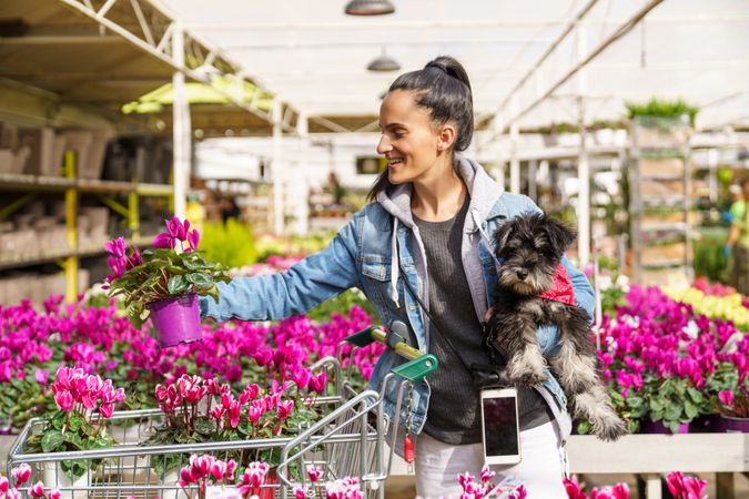 Smiling Hispanic woman with dog choosing potted plants