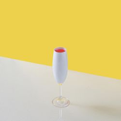 Champagne glass with pink drink against yellow and blue background