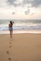 Woman in beachwear walking on sand barefoot