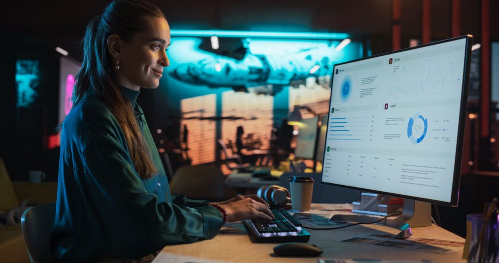 Female Digital Marketing Specialist Working on Computer at Office in the Evening.
