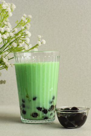 Green boba drink staged next to plant