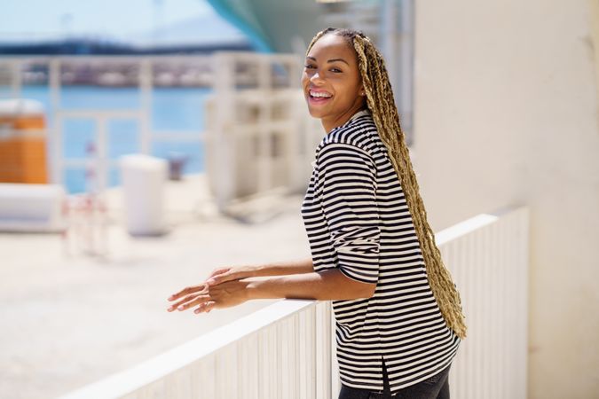 Happy female leaning on railing of the pier looking around
