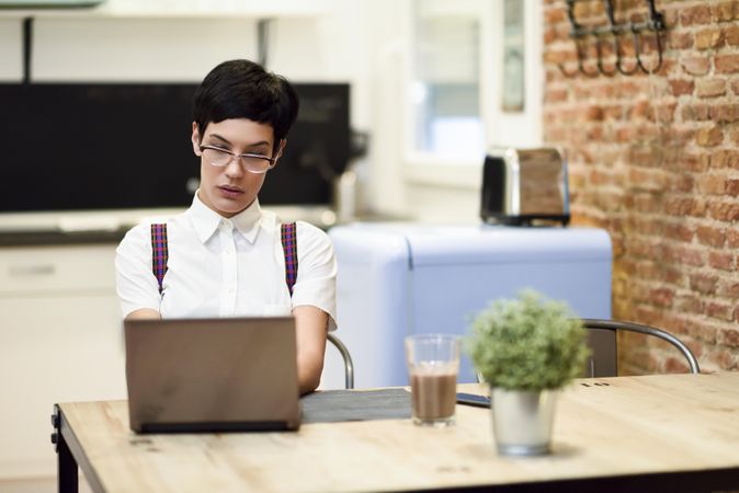 Serious woman in loft apartment working on computer at table