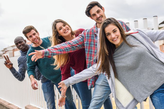 Male and female friends smiling while hanging from fence outside