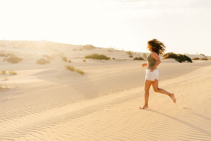 Active woman running in dry desert barefoot