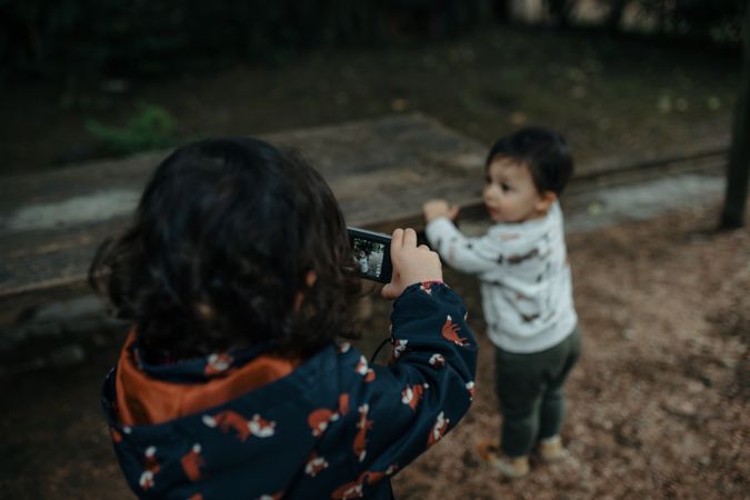 Little girl taking a photo of her brother
