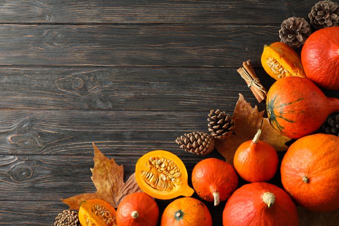Composition with pumpkins, pine cones and leaves on wooden background, copy space