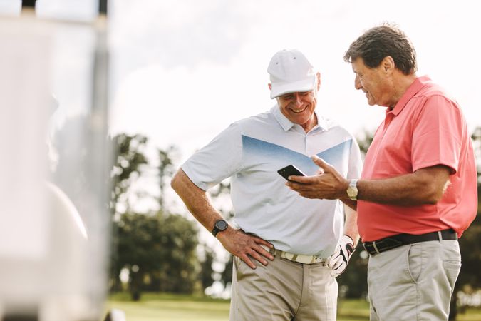 Two golf players standing together using mobile phone