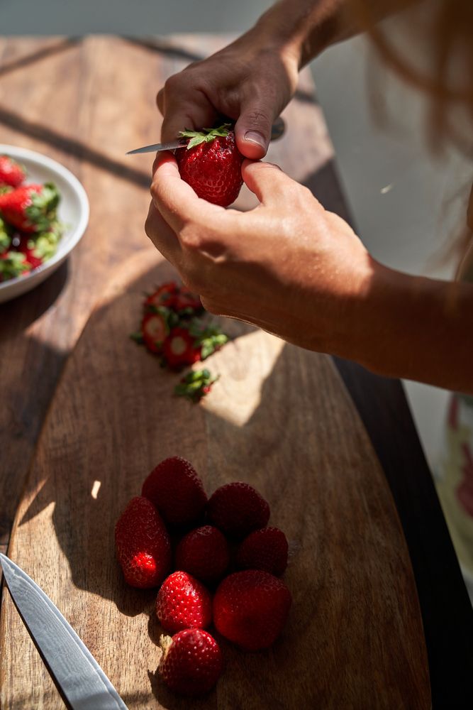 Crop woman cutting ripe strawberries