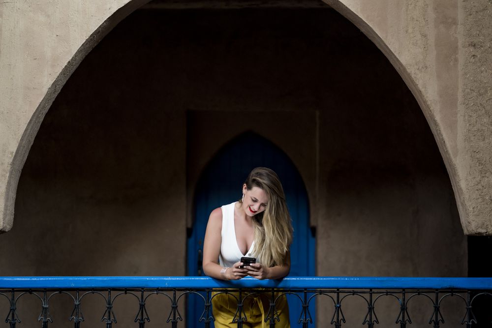 Smiling woman using smartphone on old balcony
