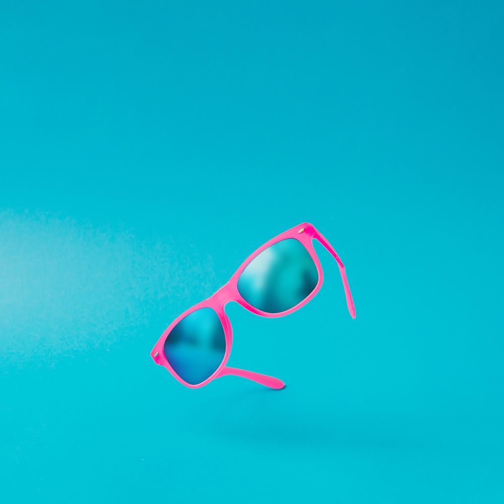 Pink sunglasses on blue background
