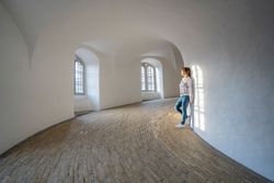 Casual woman leaning on wall in spacious gallery with windows