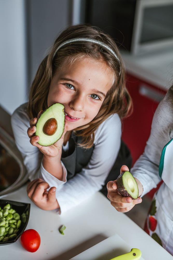 Little girl showing cut avocado