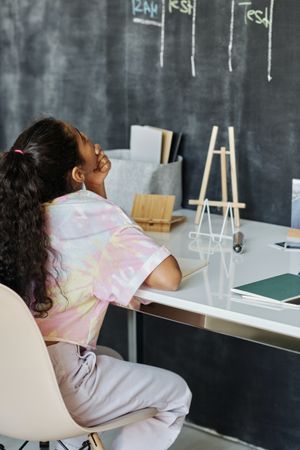 Back view of girl sitting at a desk looking at chalk board