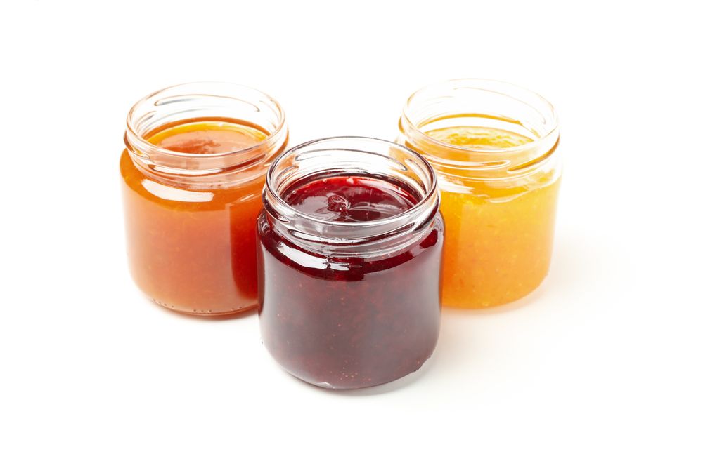 Glass jars with jam isolated on blank background
