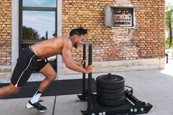 Black guy pulling weights in outdoor gym
