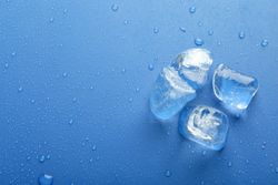 Top view of four melting ice cubed on blue table with copy space