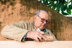Mature man shaping wood with plane tool