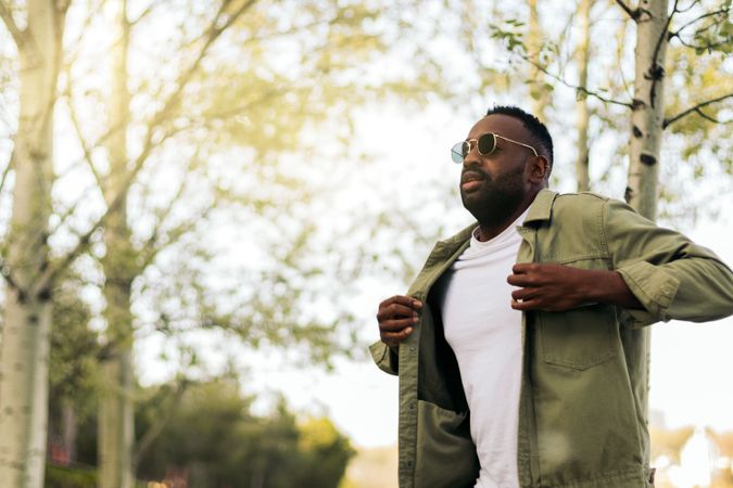 Stylish Black young man with sunglasses walking in a park