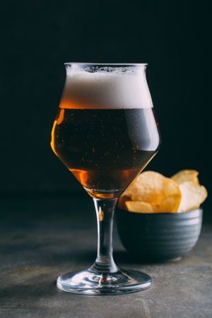 Glass of beer and chips on dark and grunge background