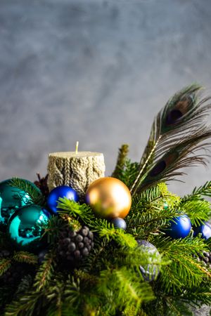 Side view of Christmas decorations in pine centerpiece with candle and peacock feathers