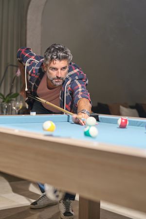 Focused mature Hispanic man playing pool