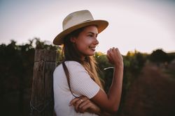 Portrait of a young woman leaning on a post outdoors