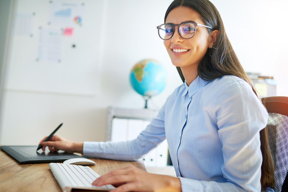 Smiling female graphic designer working on digital pad in her office