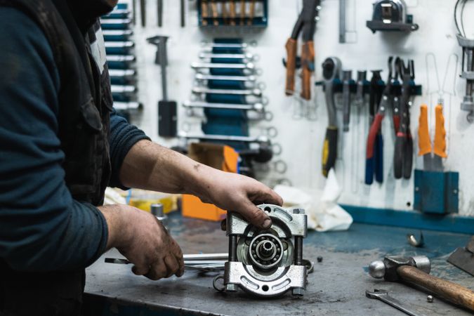 Professional mechanic assembling vehicle engine details at workbench