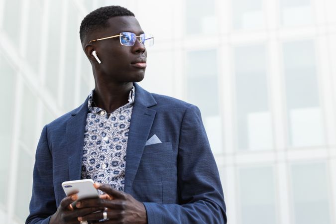 Stylish Black entrepreneur in earbud with smartphone