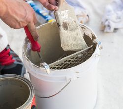 Professional Painter Loading Paint Onto Brush From Bucket