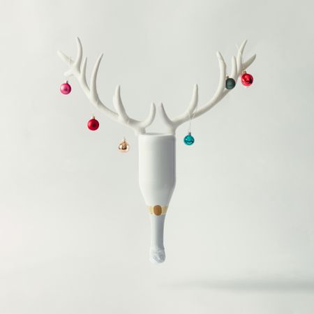 Champagne bottle with reindeer antlers and Christmas baubles