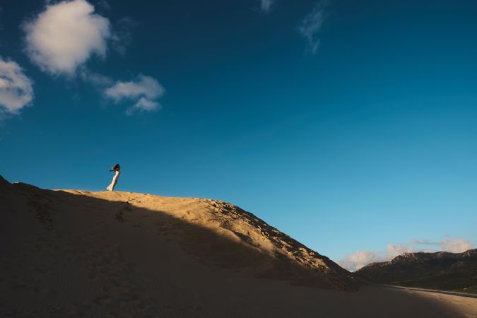 Sun lighted sandy hill with blue sky and white cloud