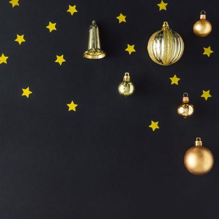 Golden Christmas decorations of stars, bells and baubles on dark background