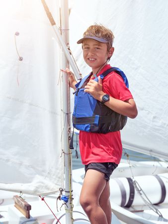 Smiling boy standing on sailboat