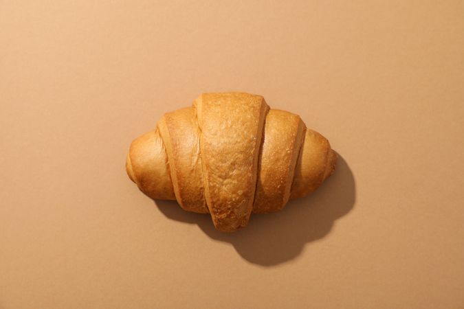 Freshly baked croissant on nude background, top view