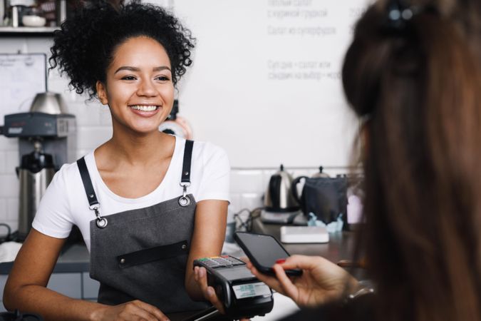 Barista taking payment from customer using smart phone