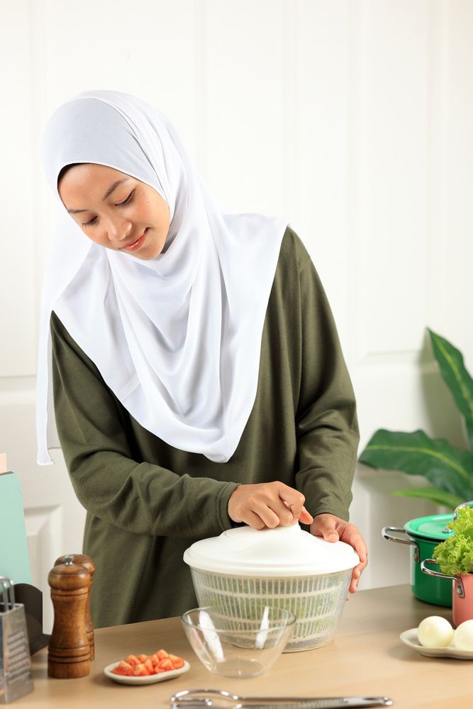 Woman in Hijab  Drains Lettuce from the Water in a Salad Spinner