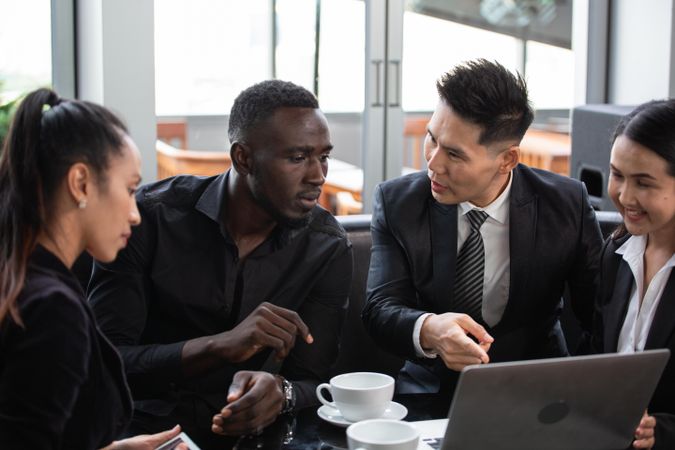 Diverse group of business people having a meeting in coffee shop over laptop