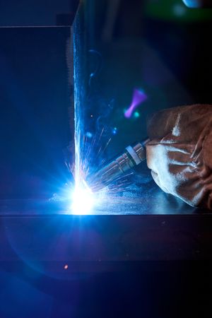Unrecognizable welder using welding machine in darkness