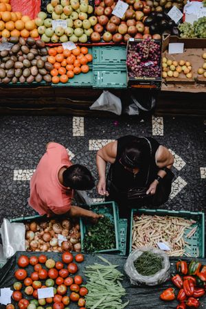 Top view of two people standing beside vegetable stand at the street market