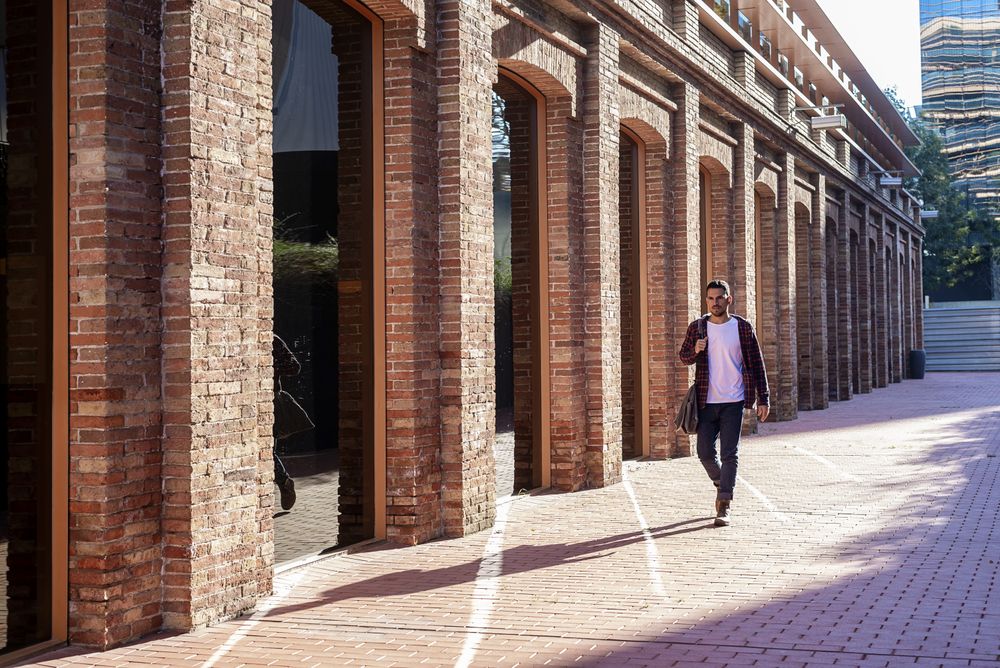 Bearded man holding shoulder bag while walking through business district