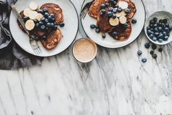 Breakfast banana pancakes with blueberry, honey, coffee, top view, horizontal, with copy space
